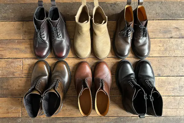Flat lay of men's leather boots: chelsea, suede chukka, moc-toe work boots and combat boots