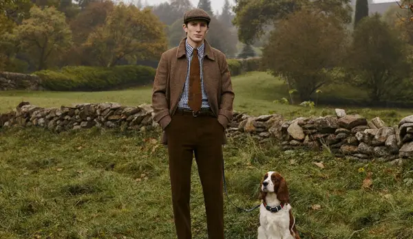 Man in a tweed jacket, flat cap and corduroys with a spaniel in the English countryside