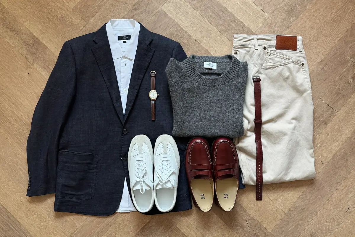Flat lay of a men's capsule wardrobe with blazer, oxford shirt, jeans, chinos and shoes