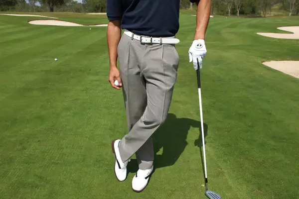 Man in a navy golf polo and stone chinos on a golf course fairway