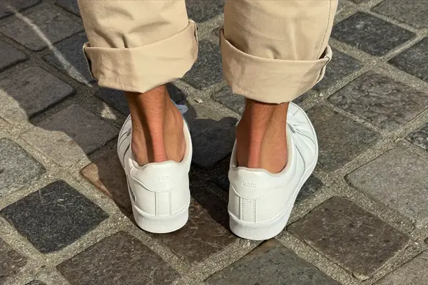 Man in cuffed beige chinos and white leather sneakers with no-show socks