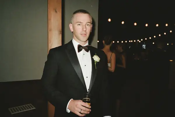 Man in a black tuxedo and bow tie at an evening wedding reception