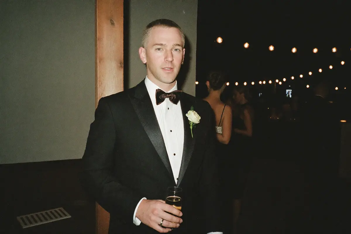 Man in a black tuxedo and bow tie at an evening wedding reception